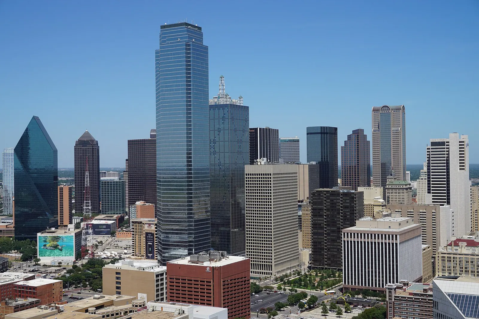 Downtown Dallas skyline seen from Reunion Tower on a clear day, with glass office towers rising above lower buildings and a small park below