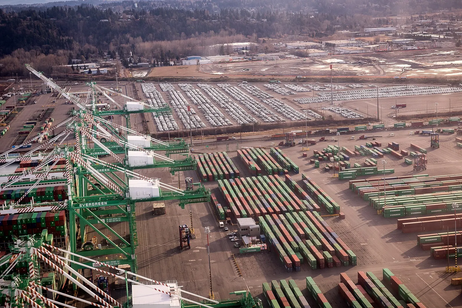 Aerial view of the Port of Tacoma container terminal with green ship-to-shore cranes and stacks of colored containers
